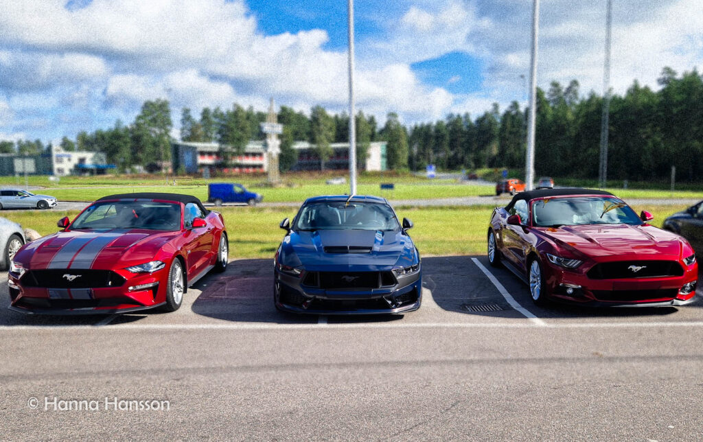 Tre Mustang-bilar i färgerna röd, blå och röd parkerade sida vid sida.